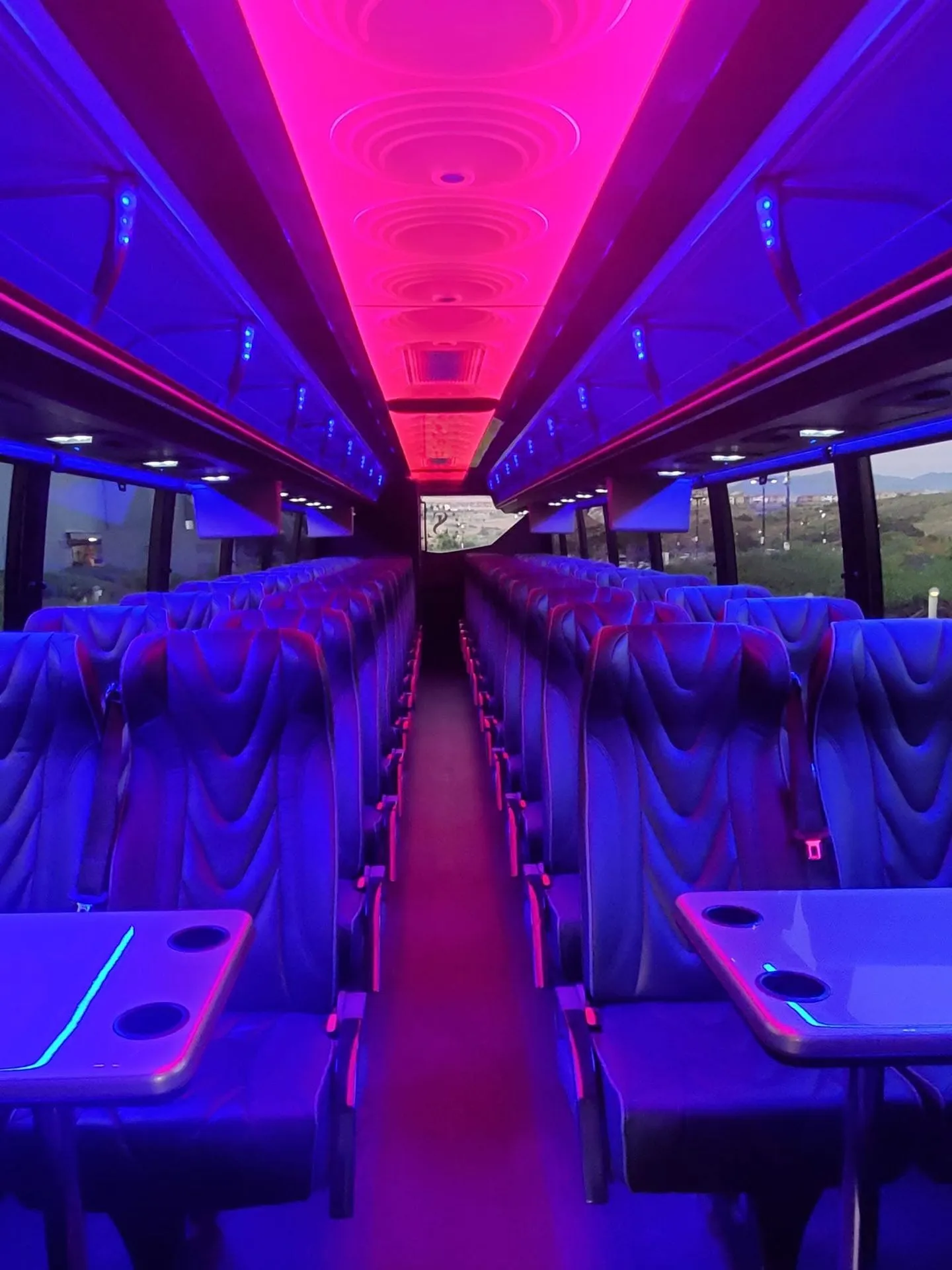 Spacious charter bus cabin with rows of seats and colorful interior lighting